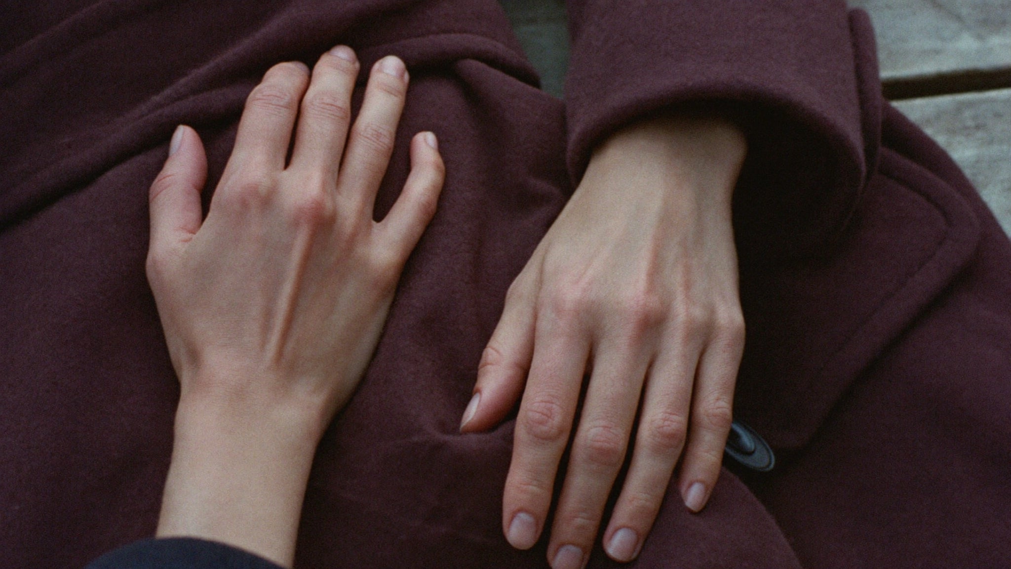 Hands carefully folding a camel wool coat