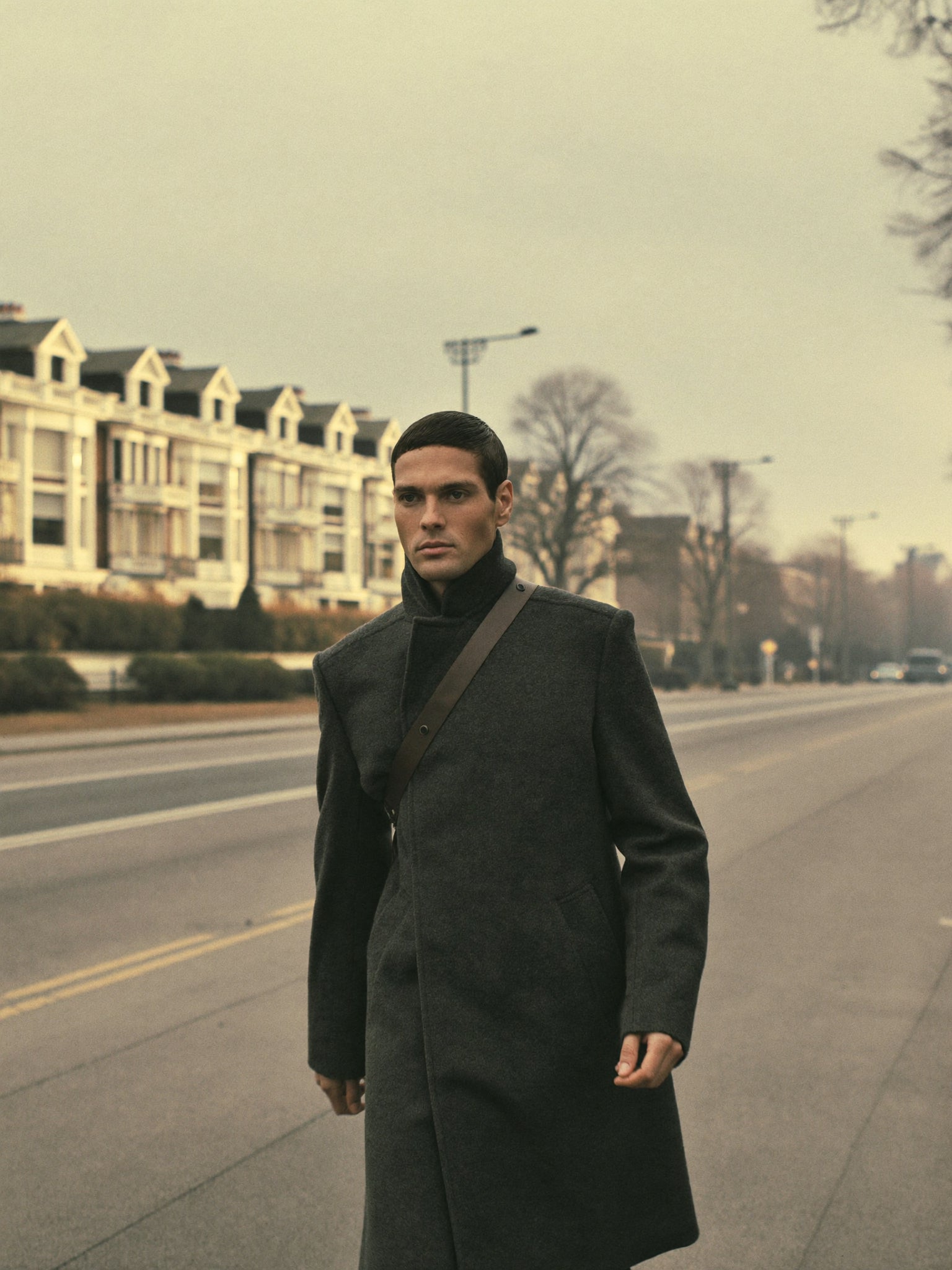 A man in a dark wool coat walking on an autumn London street