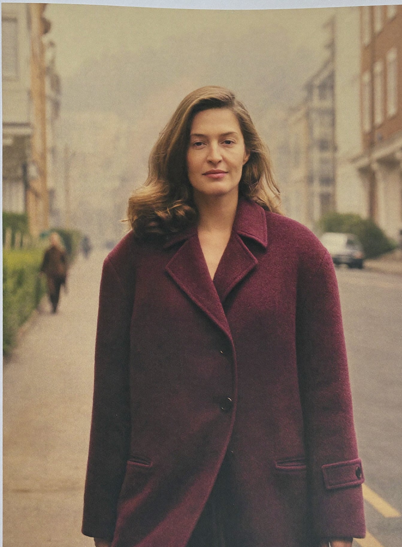 A woman in a camel coat walking on an autumn London street